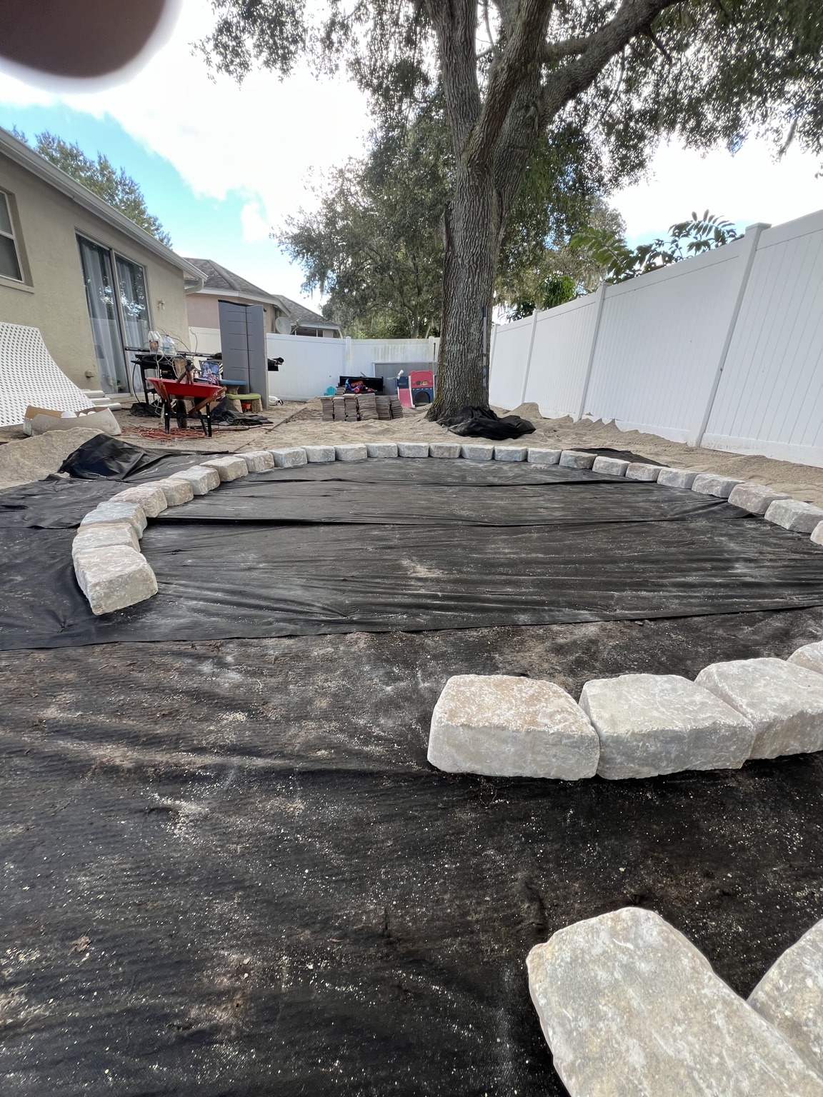 Landscape fabric and stone edging being set near the tree