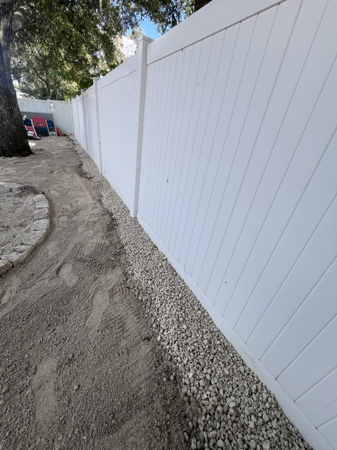 Prepared narrow path along a white privacy fence
