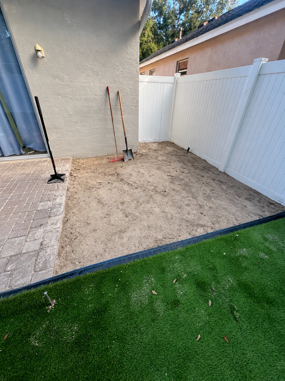 Bare side yard being prepared along the house and white fence