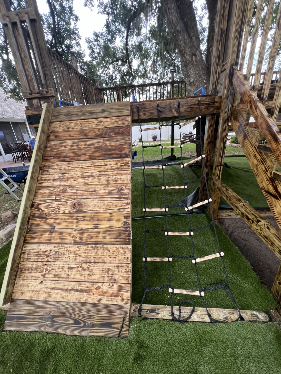 Artificial turf being fitted below a wooden play structure